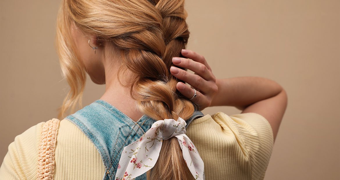 mulher branca com cabelo loiro com penteado de trança embutida com laço